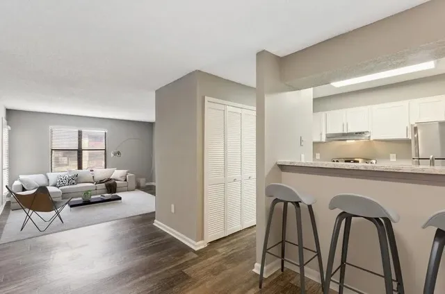 a open kitchen with stainless steel appliances granite countertop a stove a sink a refrigerator with white cabinets and wooden floor