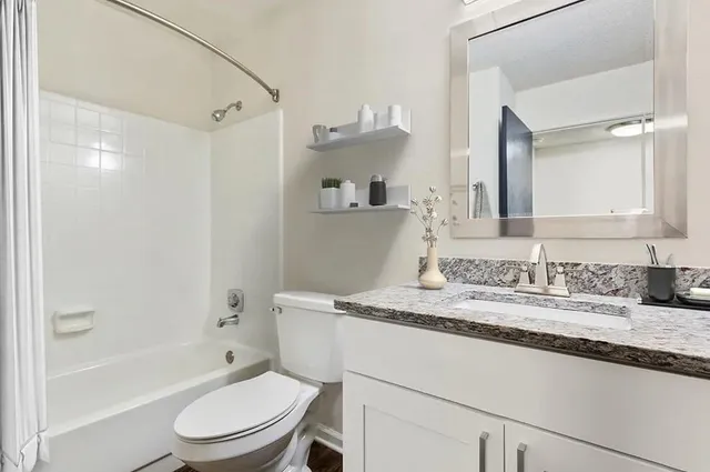 a bathroom with a granite countertop sink toilet and shower
