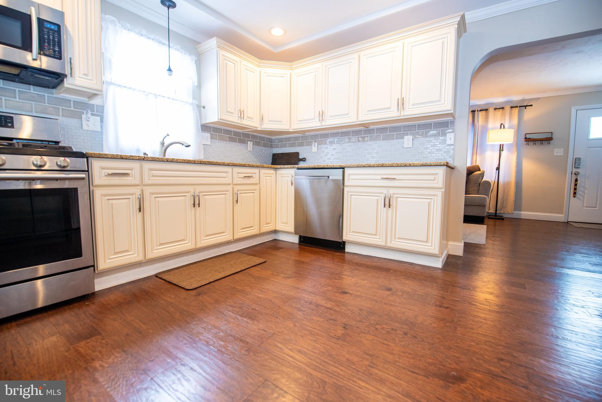 452 Elm Avenue Maple Shade, NJ 08052 - Photo 8 of 31 a kitchen with granite countertop a stove a sink and white cabinets with wooden floor