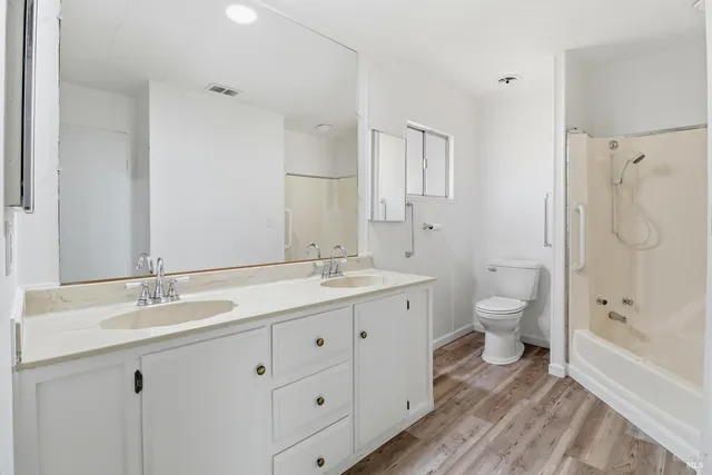 a spacious bathroom with a double vanity sink toilet mirror and shower
