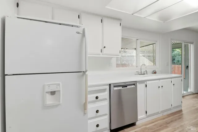 a kitchen with white cabinets and white refrigerator