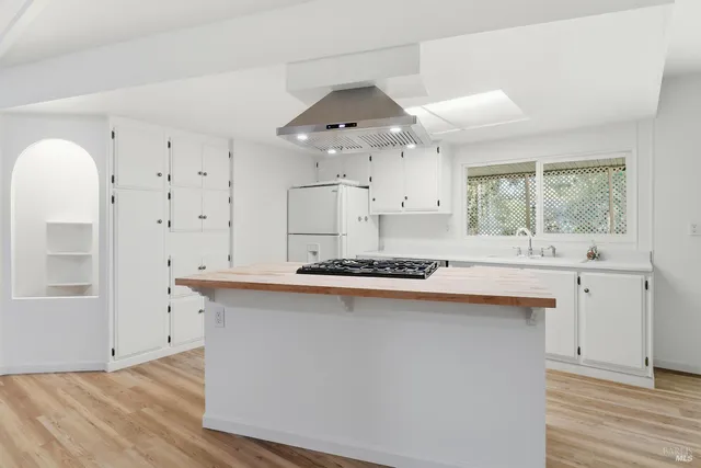 a kitchen with stainless steel appliances a stove a sink dishwasher and white cabinets with wooden floor