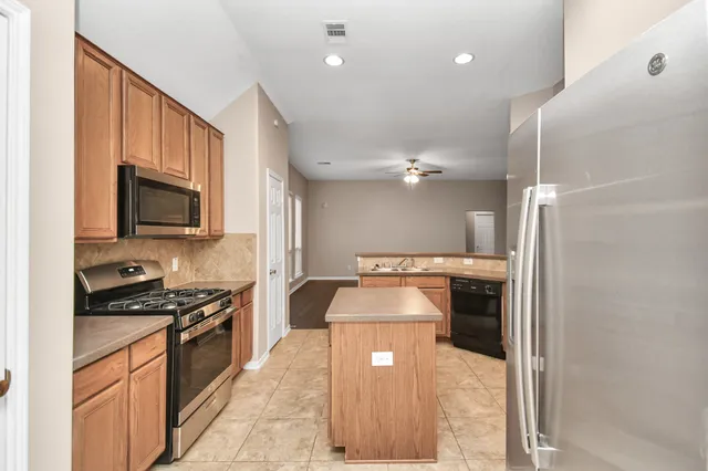 a kitchen with kitchen island granite countertop a stove and a refrigerator