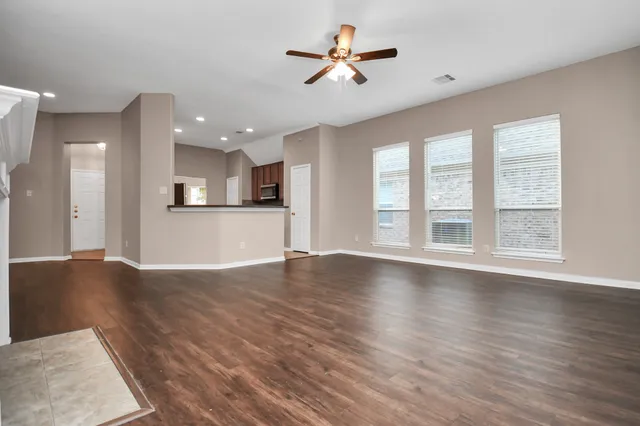 a view of an empty room with a kitchen and wooden floor