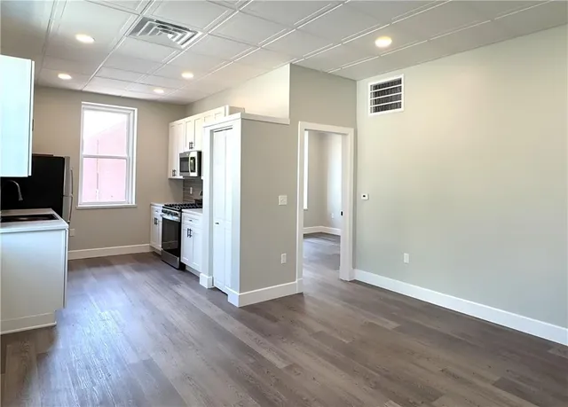 a view of a kitchen with wooden floor and electronic appliances