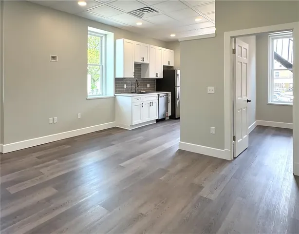 a view of a kitchen with a sink and dishwasher with wooden floor