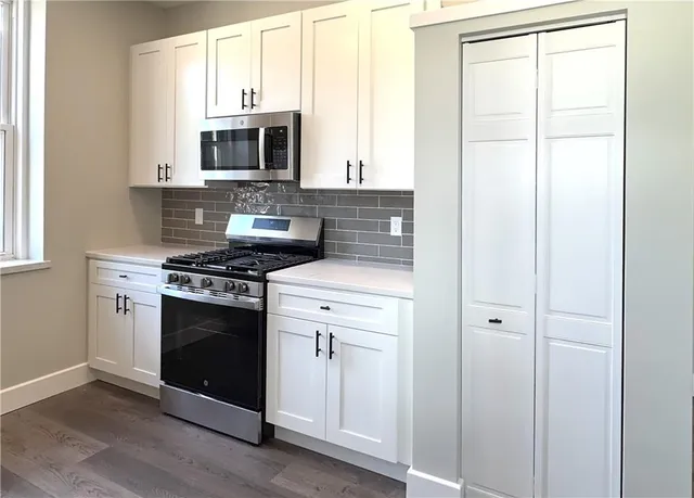 a kitchen with stainless steel appliances a stove a microwave and a window