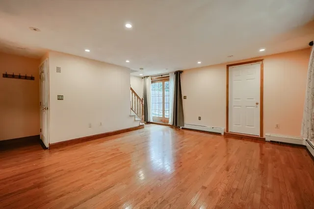a view of an empty room with wooden floor and closet