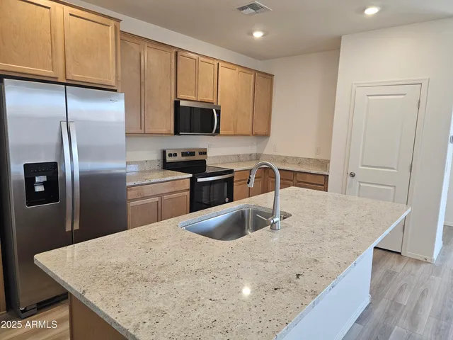 a kitchen with stainless steel appliances granite countertop a sink a microwave a refrigerator and white cabinets