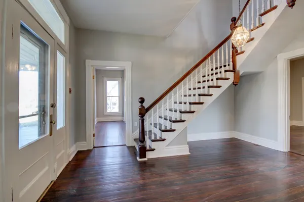 a view of an empty room with wooden floor and a fireplace