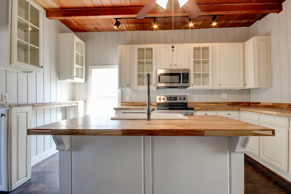 a kitchen with stainless steel appliances granite countertop a sink a stove and a microwave oven with white cabinets