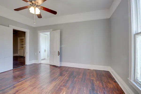 an empty room with wooden floor fireplace and windows
