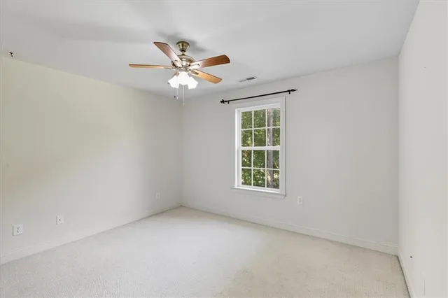 an empty room with a window and ceiling fan
