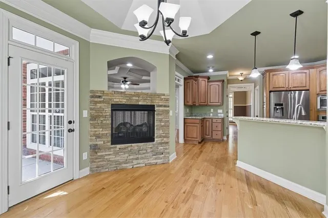 a living room with stainless steel appliances furniture a fireplace a flat screen tv and a kitchen view