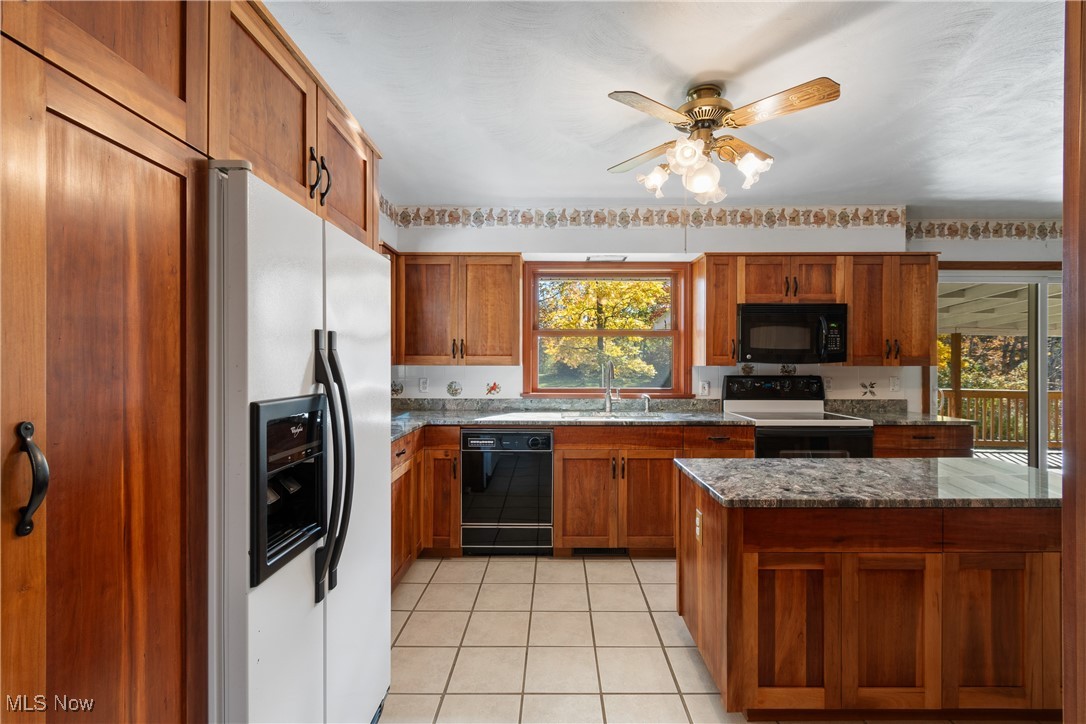 3240 Copley Road Akron, OH 44321 - Photo 11 of 35 Kitchen featuring sink, black appliances, dark stone counters, ceiling fan, and light tile patterned floors