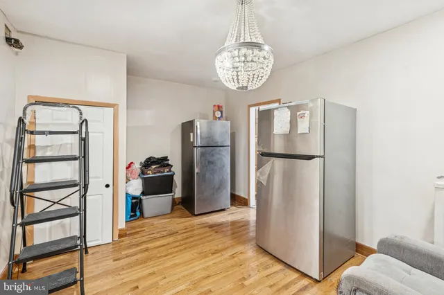 a view of a refrigerator in kitchen and an empty room