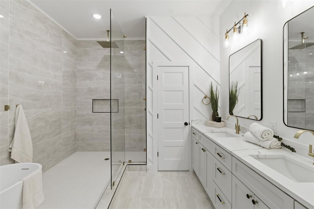 435 Waterboard Road Trinidad, TX 75163 - Photo 31 of 39 Contemporary bathroom featuring a spacious walk-in shower with a built-in niche and rainfall showerhead, dual vanities with undermount sinks, stone countertops, and gold-finish fixtures