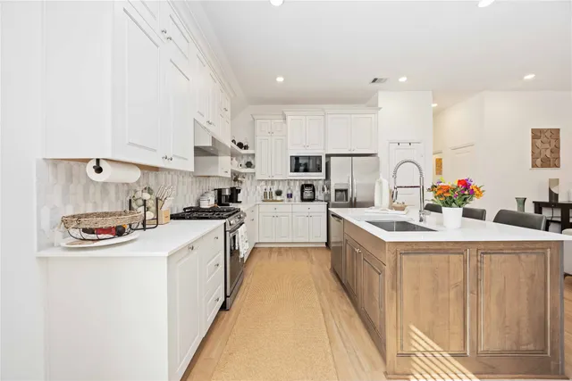 a kitchen that has a lot of white cabinets and stainless steel appliances