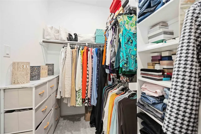a view of walk in closet with clothes and shoes