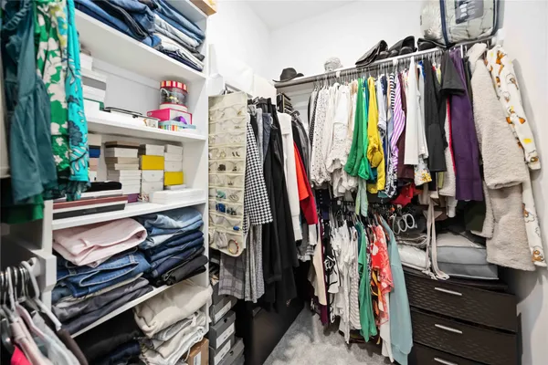 a view of walk in closet with clothes and shoes