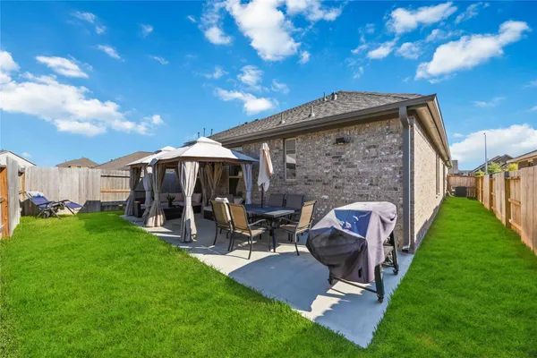 a view of a patio with table and chairs and a barbeque