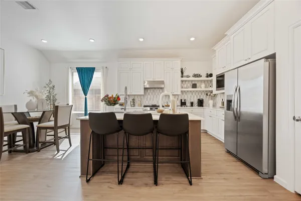 a kitchen with a dining table chairs and refrigerator