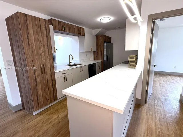 a kitchen with stainless steel appliances a refrigerator and wooden floor