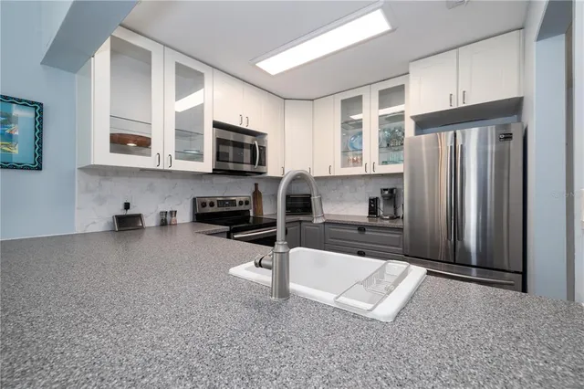 a kitchen with stainless steel appliances a refrigerator sink and microwave