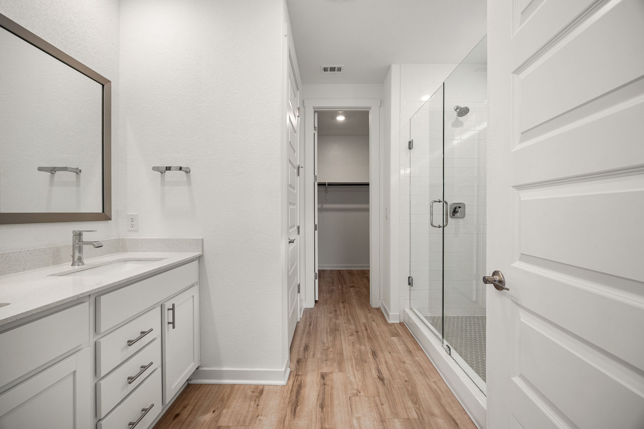 904 Balsora Cove Georgetown, TX 78628 - Photo 21 of 40 Full bath featuring double vanity, a walk in closet, a stall shower, and wood-like vynil flooring flooring