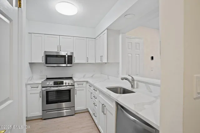 a kitchen with stainless steel appliances granite countertop white cabinets a sink and a stove