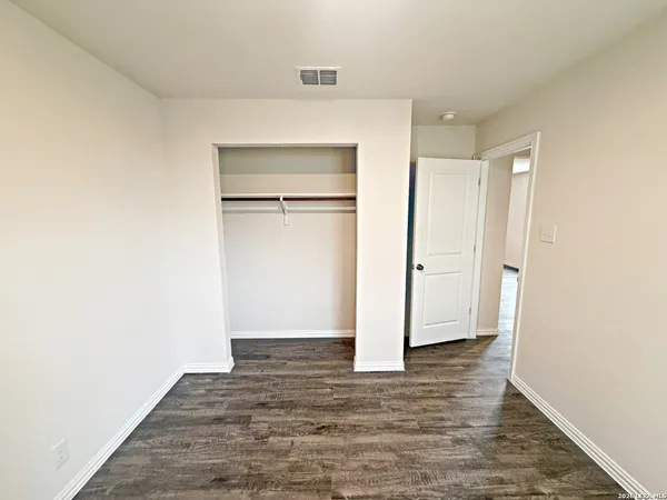 a view of an empty room with wooden floor and closet