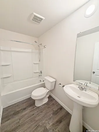 a bathroom with a sink a toilet a mirror and shower