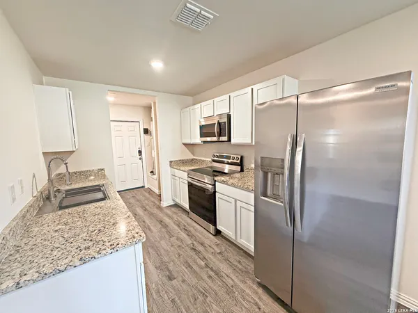 a kitchen with stainless steel appliances granite countertop a refrigerator and a sink