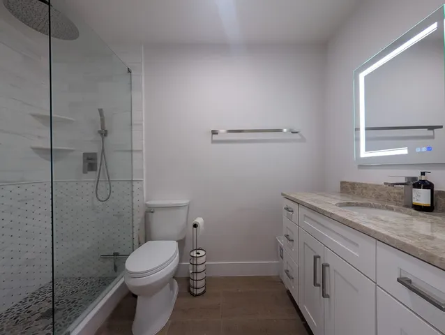 a bathroom with a granite countertop toilet and a sink