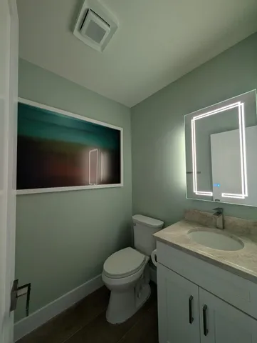 a bathroom with a granite countertop toilet sink and mirror