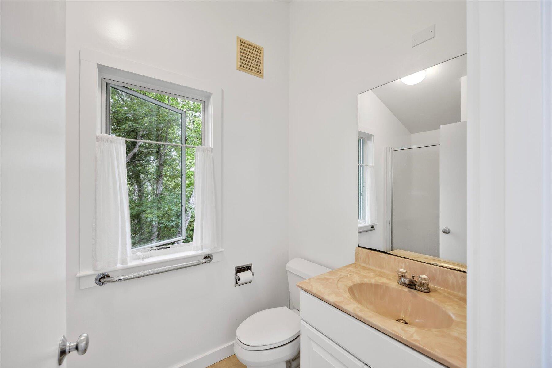 44 Nobska Road Woods Hole, MA 02543 - Photo 17 of 47 a bathroom with a granite countertop sink toilet a large mirror and a window