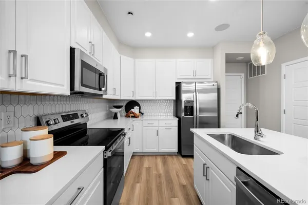 a kitchen with a dining table cabinets appliances and wooden floor