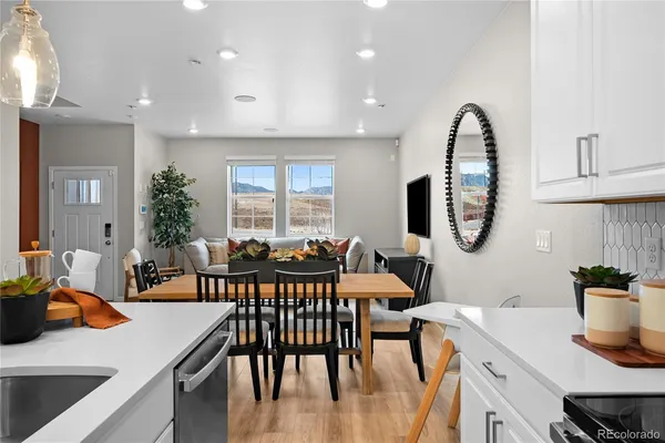 a kitchen with stainless steel appliances a dining table chairs stove refrigerator and cabinets