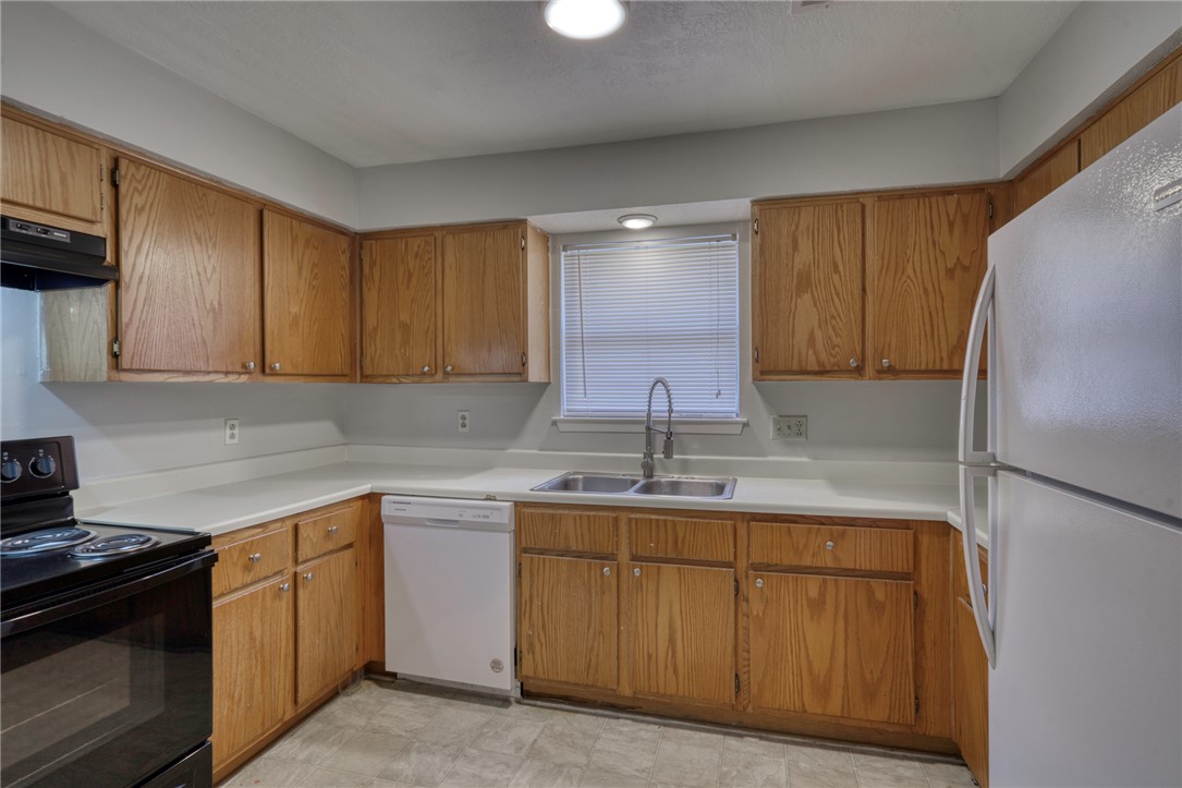 902 Spring Loop, Unit B College Station, TX 77840 - Photo 6 of 10 Kitchen with white appliances, light countertops, brown cabinets, and under cabinet range hood