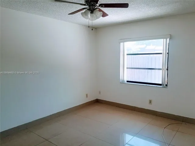 an empty room with a window and ceiling fan