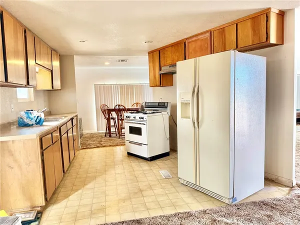 a kitchen with stainless steel appliances a refrigerator a stove a sink a washer dryer and a dining table