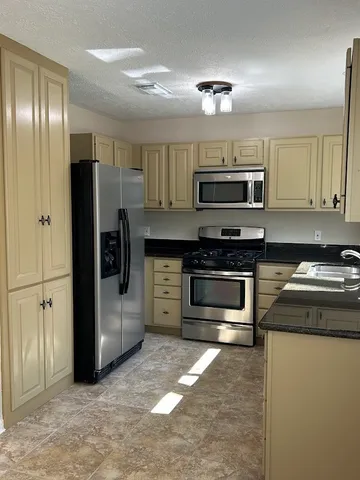a kitchen with stainless steel appliances granite countertop a refrigerator and a stove top oven