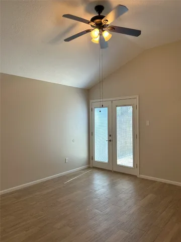 an empty room with wooden floor fan and windows