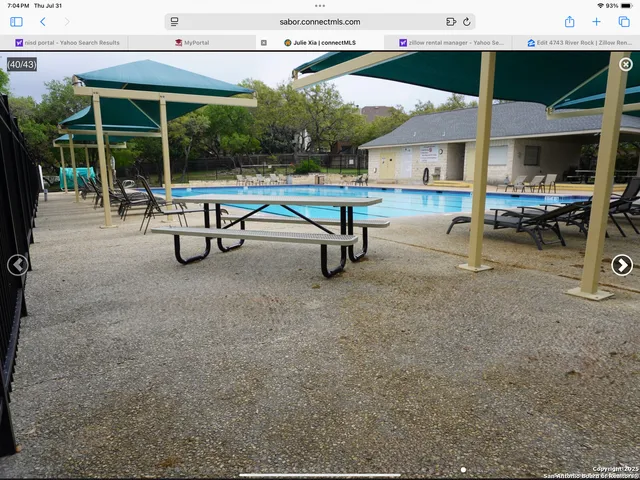 an outdoor sitting area with chairs and table under an umbrella