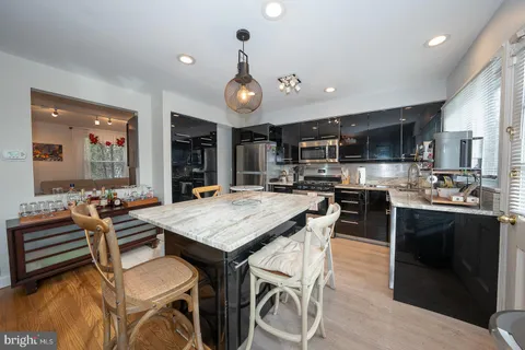 a room with stainless steel appliances kitchen island granite countertop a stove a sink a dining table and chairs