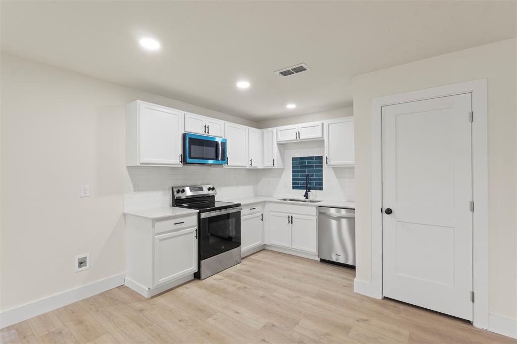 5124 Kilpatrick Avenue Fort Worth, TX 76107 - Photo 8 of 31 a kitchen with stainless steel appliances granite countertop a stove top oven a sink dishwasher and a refrigerator with wooden floor