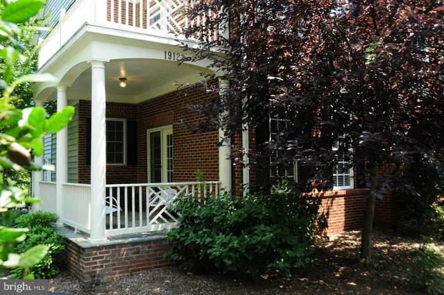 a view of a house with a small yard plants and large tree