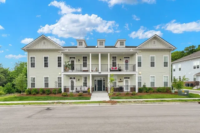 a view of a white house with a small yard and plants