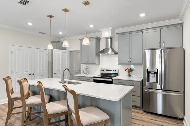 a kitchen with stainless steel appliances kitchen island granite countertop a sink a stove and a wooden floors