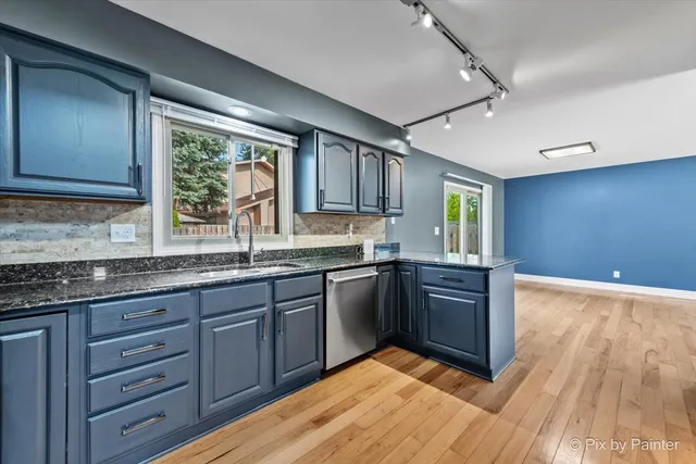 a kitchen with granite countertop wooden floors and sink